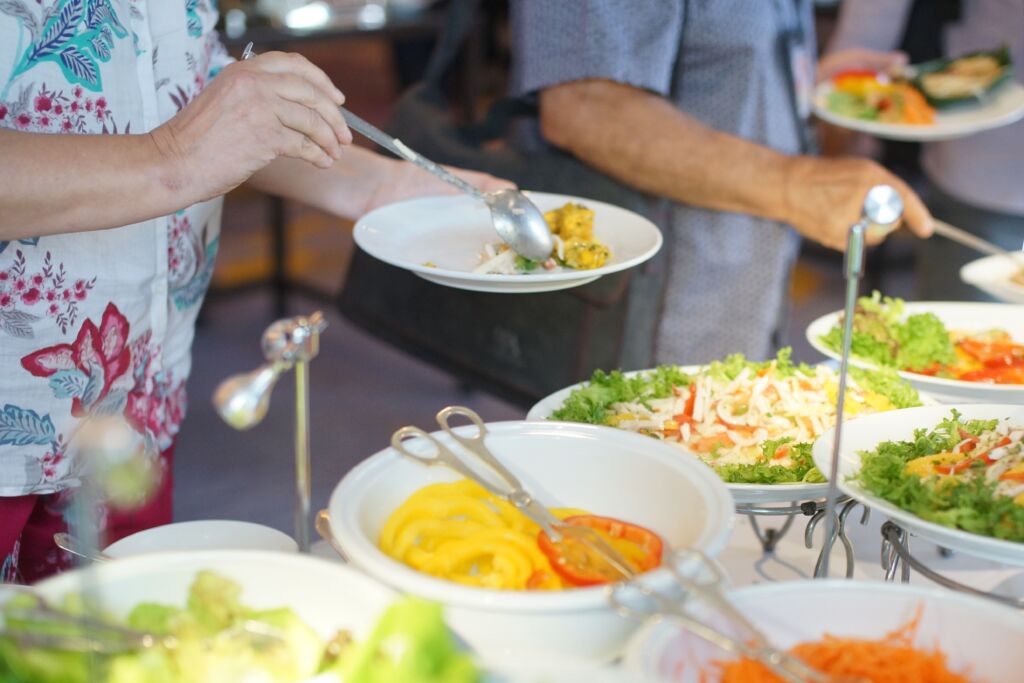 Senior elderly people queuing to take food from the buffet line, using their senior citizen discounts.
