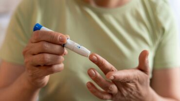 image of an elderly woman pricking her finger for in-home blood test to check sugar level