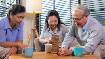 A trio of elderly seniors playing wooden blocks game in a senior daycare, also known as senior enrichment centre