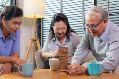 A trio of elderly seniors playing wooden blocks game in a senior daycare, also known as senior enrichment centre