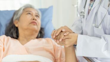 Image of an elderly woman hospitalised and being cared for by medical professionals, either via geriatric, palliative, or rehabilitative care option