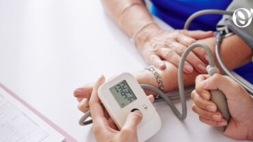 Image of an elderly woman taking her blood pressure reading