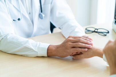 Hand of doctor reassuring an elderly patient with the assistance from a senior concierge